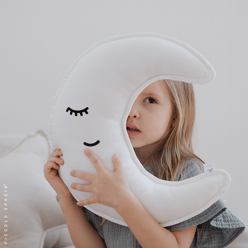 Niña jugando con un cojín en forma de luna blanca-Piccolo Spazio